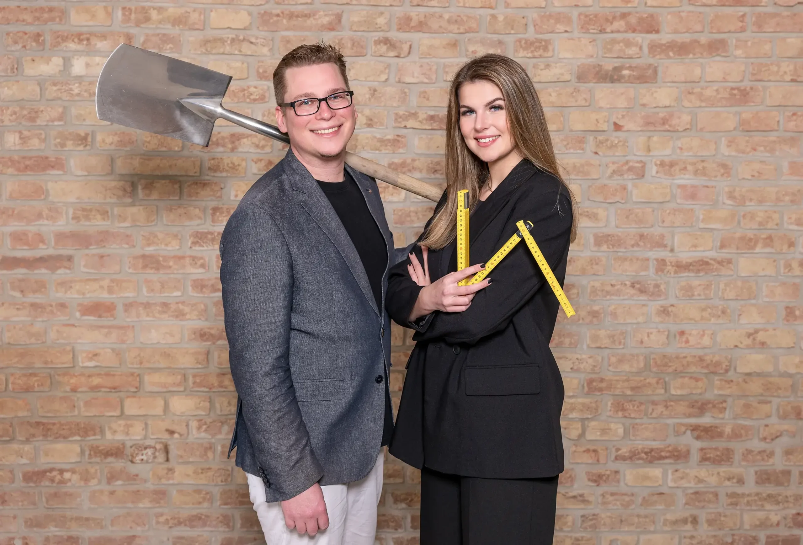 Businessportrait von Baumeister und Ingenieur vor Ziegelwand mit Werkzeug als authentische Darstellung