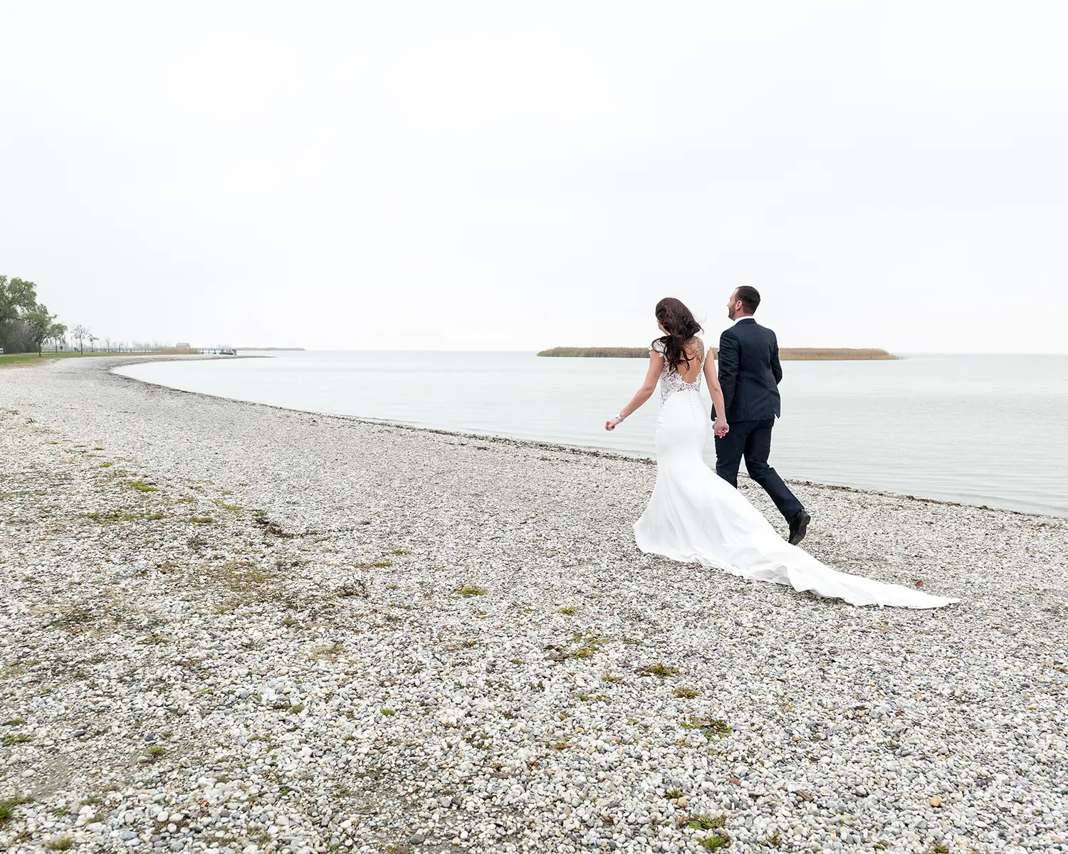 Brautpaar spaziert am Seeufer in natürlicher und emotionaler Hochzeitsfotografie