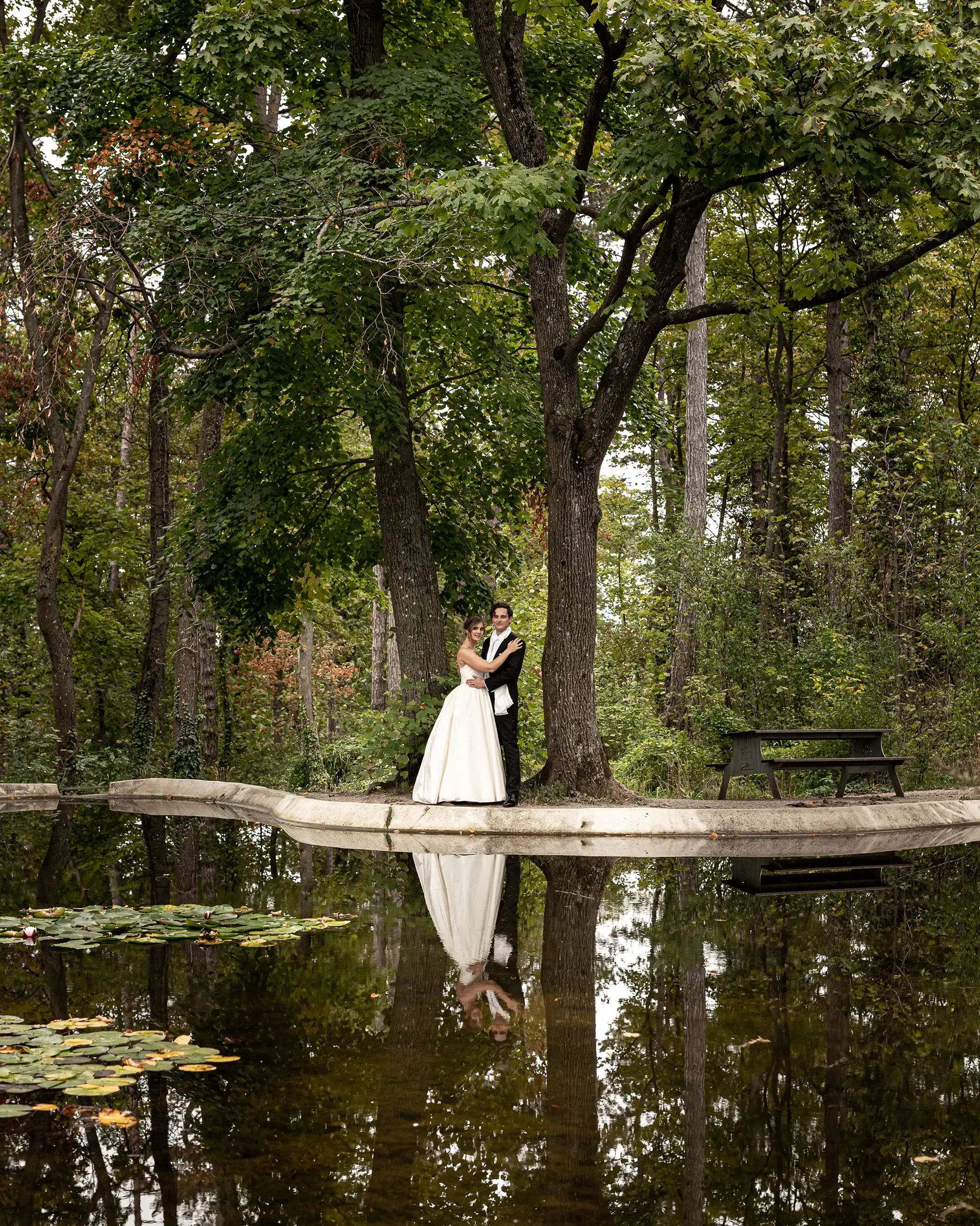 Brautpaar am Teich mit Spiegelung im Wasser als emotionale Hochzeitsaufnahme