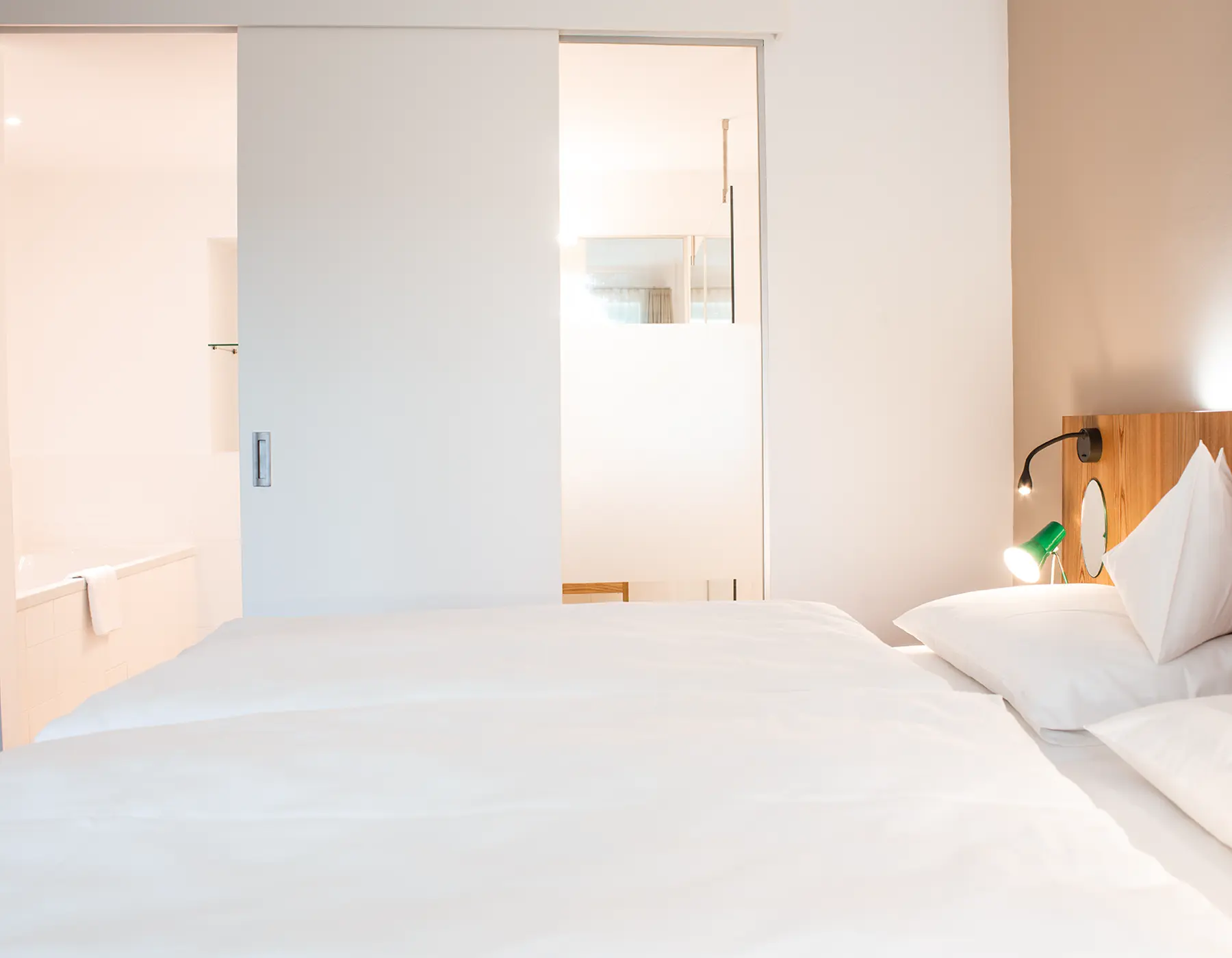 Helles Hotelzimmer mit Blick vom Bett ins Badezimmer in moderner Innenarchitektur