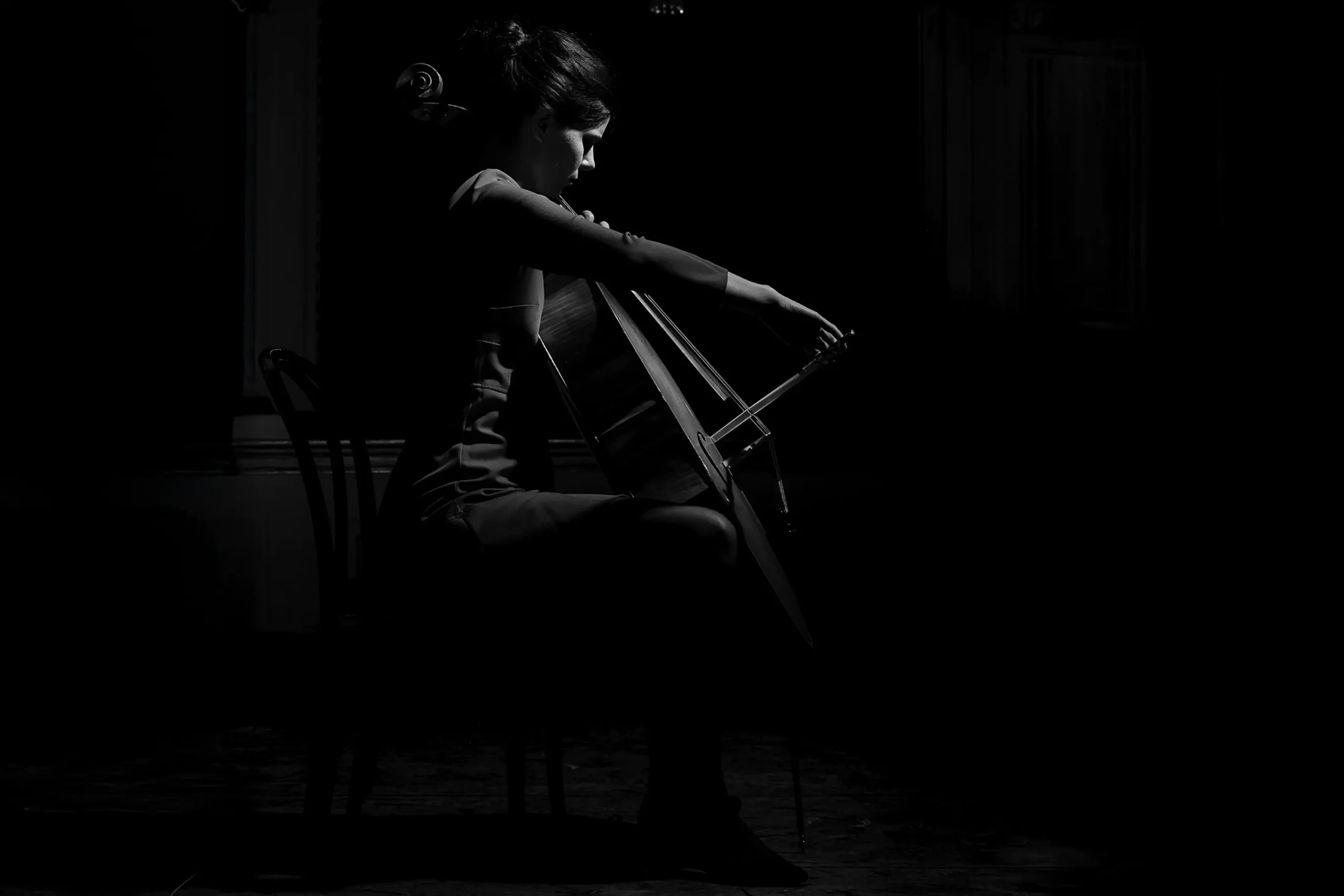 Künstlerportrait einer Cellistin vor dunklem Hintergrund mit dezenter Lichtführung