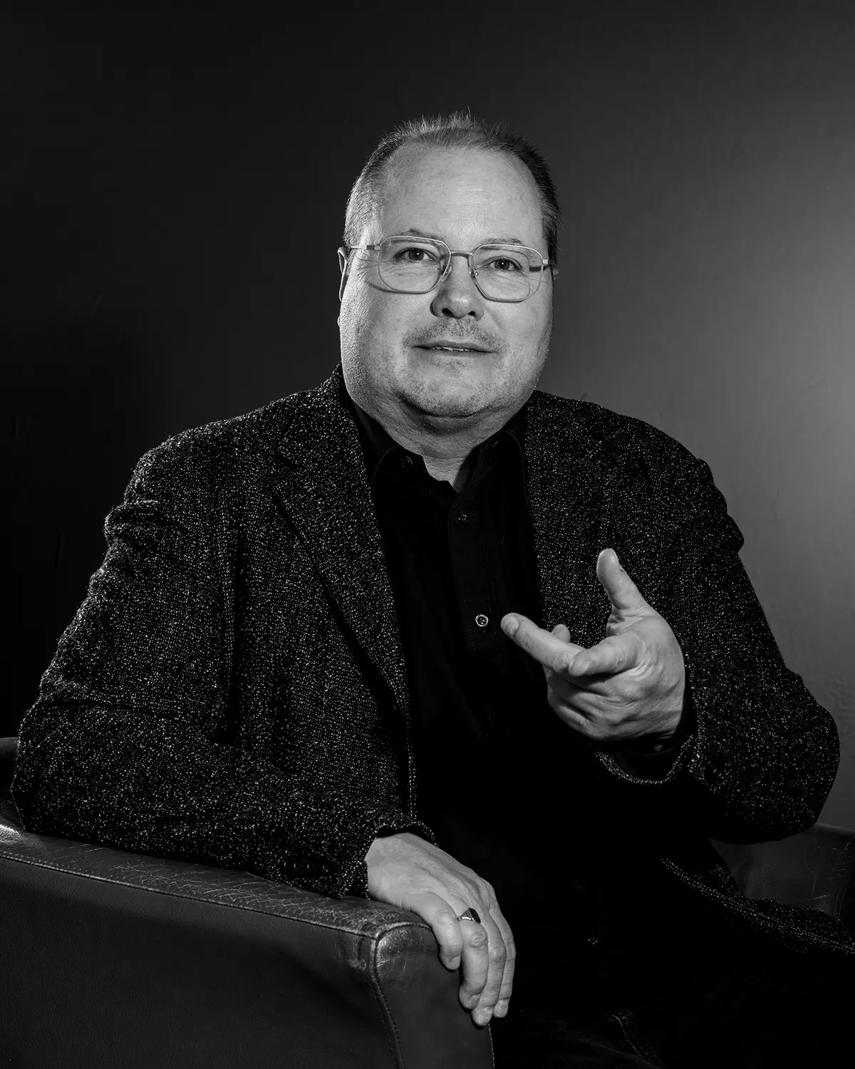 Portrait eines Mannes mit natürlichem Lachen auf einem Sessel in reduzierter Bildgestaltung